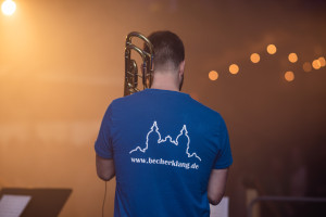 Jonas mit Posaune von hinten auf der Bühne fotografiert mit Dom-Silhouette und Homepageadresse